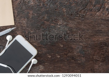 Top view laptop, smartphone, post note, pencil and earphone on old wooden background with copy space