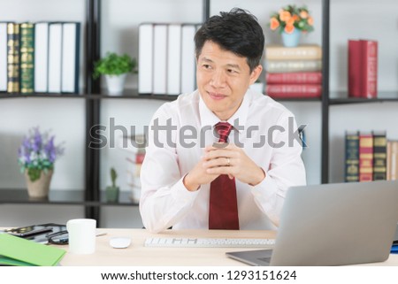 Middle aged, handsome, Asian, businessman, in white shirt, dark red necktie, sitting in his startup office, crossed hands, posing proudly at working desk, with notebook and coffee cup on background