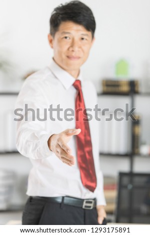 Close up portrait of middle aged, handsome, Asian, businessman, in white shirt, necktie, black pants posing handshake sign for greeting and welcoming sign, on isolated white background