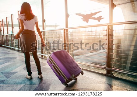 Young woman pulling suitcase in  airport terminal. Copy space Royalty-Free Stock Photo #1293178225