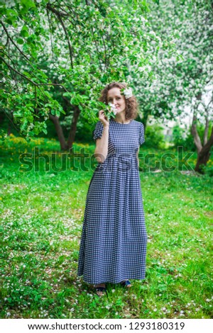 Happy young woman enjoying smell in a flowering spring garden. Beautiful curly girl enjoying beauty of apple blossom