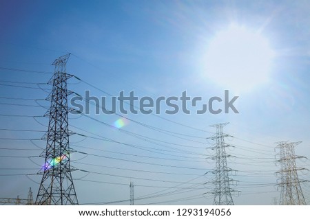 high-voltage electric poles have light from the sun shining in the daytime
