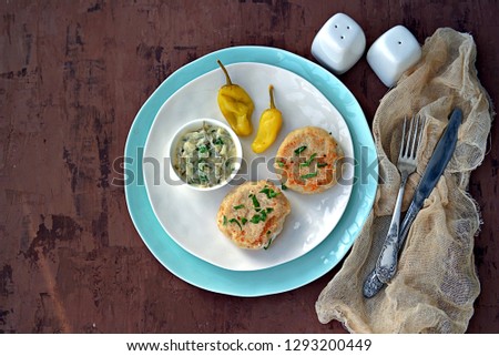 Homemade fish cakes on a white plate. Served with tartar sauce and marinated hot pepper.