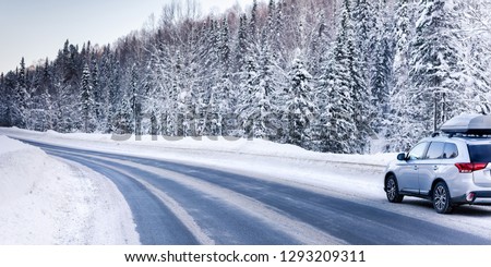 Suv car with rooftop cargo carrier trunk stay on roadside of winter road. Family trip to ski resort. Winter holidays adventure. car on winter road Royalty-Free Stock Photo #1293209311