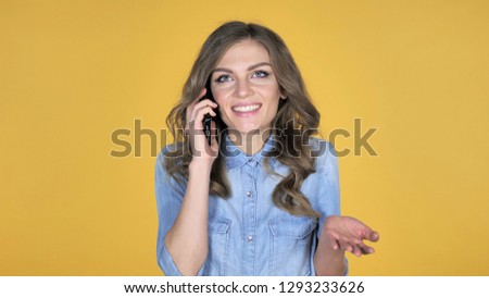 Excited Young Girl Talking on Smartphone, Yellow Background