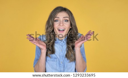 Happy Amazed Young Girl Surprised by Gift Isolated on Yellow Background