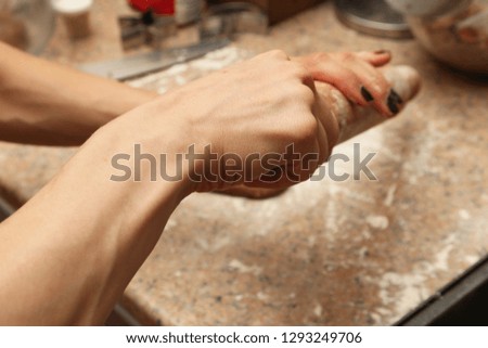 A women's hands holding a dough rolling pin. This image can be used to represent cooking or baking in the kitchen. 