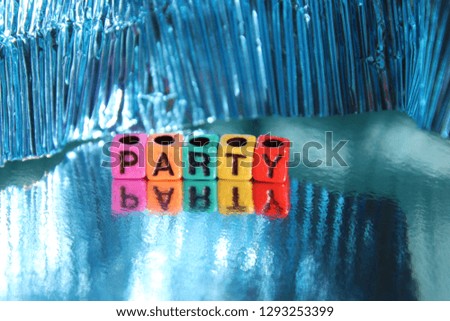 Party word spelled out in primary colors colorful abc alphabet beads blocks on blue wood background.