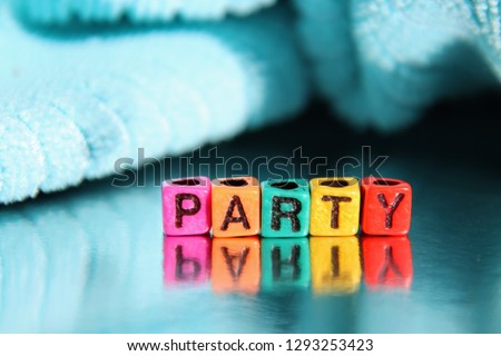 Party word spelled out in primary colors colorful abc alphabet beads blocks on blue wood background.