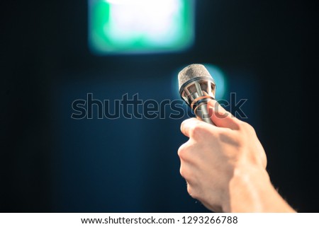 Person is holding up a metal microphone and wants to interview someone, copy space