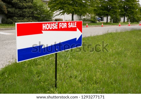 'House for sale' open house directional pointer on green lawn at road turn