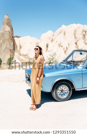 girl in a long dress leaned on an old-fashioned cabriolet