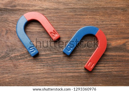Red and blue horseshoe magnets on wooden background, top view