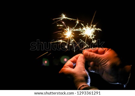 Abstract sparklers background bright festive Christmas and happy new year the man hold hand sparkler motion blurred in wind at winter dark night for celebration and hope background.Vivid black tone.