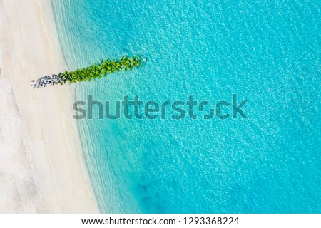 Sand beach aerial, top view of a beautiful sandy beach aerial shot with the blue waves rolling into the shore, some rocks as wave breaker 