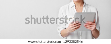 Modern woman using digital tablet computer over grey studio background