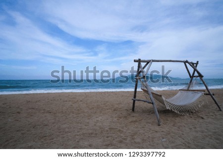 Empty hammock strung between two wooden pile on the sandy beach. Royalty high-quality stock photo image of nobody relaxing  on hammock outdoors on the sandy beach. Summer vacation leisure concept