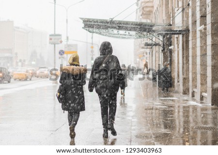 people walk in city streets under snowall