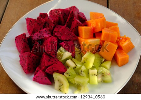 A plate with slice of papaya, red dragonfruit, and kiwi for a breakfast or salad.