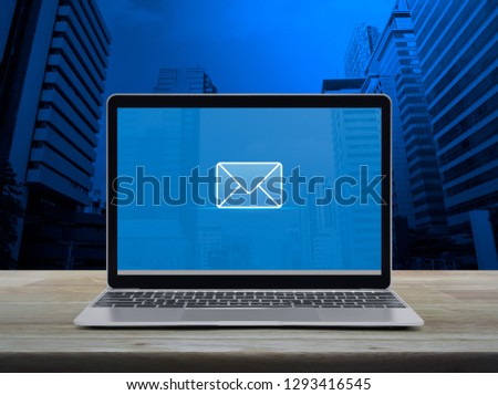 email flat icon with modern laptop computer on wooden table over office city tower and skyscraper, Business contact us concept