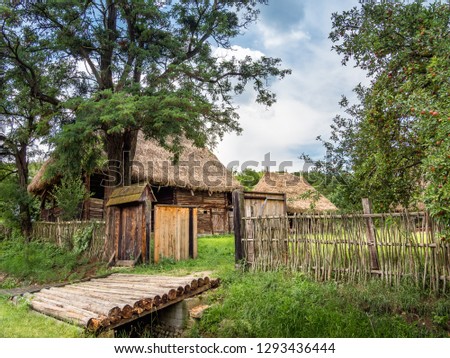 Entry into the yard of an very old house with roof of straw in Apuseni Mountains. Past life in the country in Transylvania,  Romania.  Old wooden house with roof of straws from Transylvania. Royalty-Free Stock Photo #1293436444