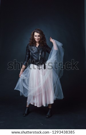 beautiful girl in a ball gown. leather jacket. photo in the studio. great sharpness. full height.