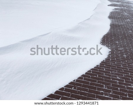 Snow drift with red brick wall in background