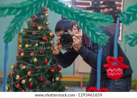 The photographer draws with the camera. In the new year's background. Handsome young photographer . photographer holding digital camera . Male photographer with professional camera .