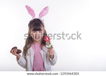 Little girl dressed as the Easter bunny standing on white background and holding chocolate Easter eggs. Child Easter Holiday Concept. Isolated.