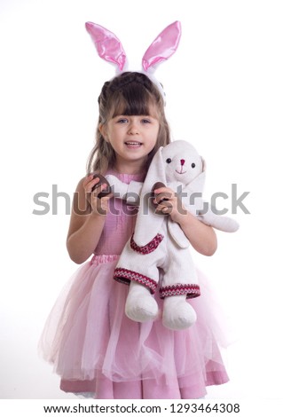 Little girl dressed as the Easter bunny standing on white background and holding bunny. Child Easter Holiday Concept. Isolated.