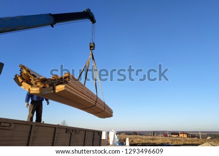 load boards supplied to the construction site with a crane, manipulator Royalty-Free Stock Photo #1293496609