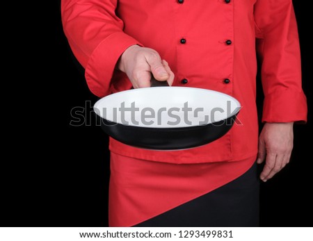 cook in red uniform holding an empty round white frying pan, black background