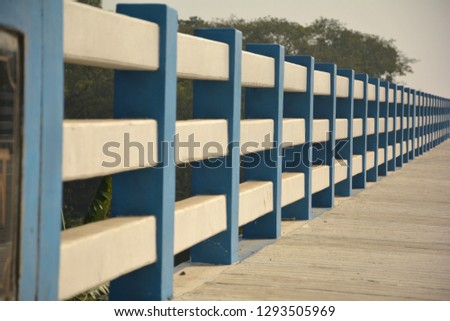 A railing of a bridge made of concrete and painted in black, white and blue colors with selective focusing and blur background.