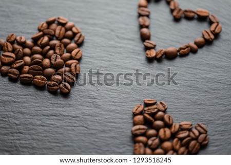 three  hearts made of coffee beans on a black slate stone surface. coffee love
