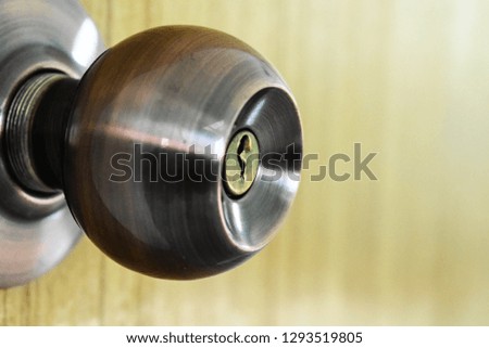 Close shot of a silver iron doorknob in a wood door.