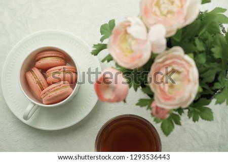 pink macarons in a cup in a table setting for tea.