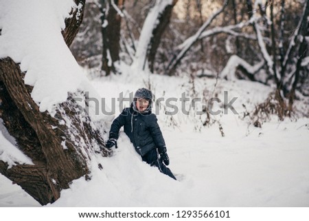 Little cute boy is having fun playing with snow in winter, Russia. Image with selective focus, noise effect and toning.