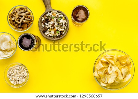 Fast food for TV watching. Snacks on desk.  Chips, nuts, rusks and beer on yellow background top view space for text