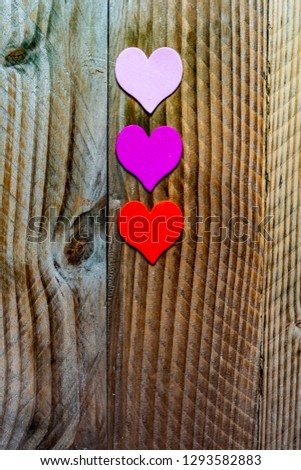 Three colored hearts on a vintage wooden background