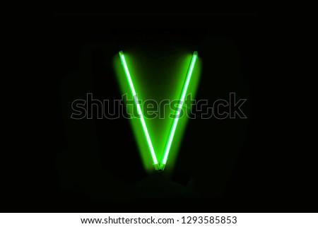 neon capital letter V lighted up. On the black background.