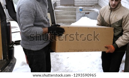 Two male porters carry heavy things. moving at winter snowy day