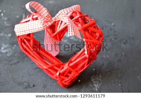 a red heart made of wood texture. A celebration of love. Valentine's day. wicker red heart with bow and ribbon on black background