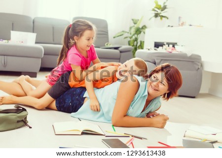 mother and children doing homework on the floor