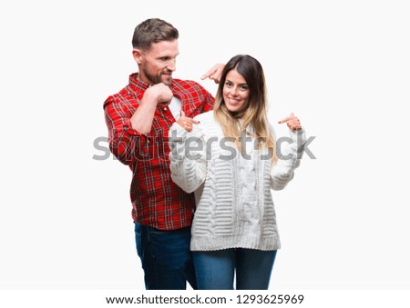 Young couple in love wearing winter sweater over isolated background looking confident with smile on face, pointing oneself with fingers proud and happy.