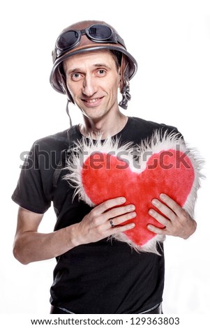 Portrait of the comic man in biker helmet with pillow in shape of heart. Isolated on white.
