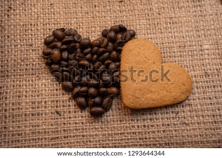 Heart coffee frame made of coffee beans on burlap texture. Romantic picture. Coffee beans in the shape of heart with a cookie. Top view.