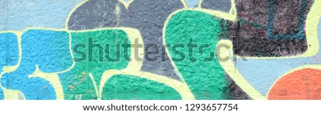 Fragment of graffiti drawings. The old wall decorated with paint stains in the style of street art culture. Colored background texture in green tones