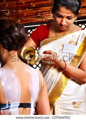 Woman having Ayurvedic spa treatment. Pouring milk.