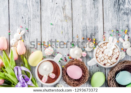 Easter funny kids food and drink concept, sweet hot chocolate with marshmallow bunny rabbits and easter eggs, wooden background copy space top view