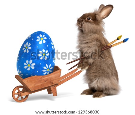 Cute Easter bunny rabbit with a little wheelbarrow and a blue painted Easter egg, isolated on white, CG+photo